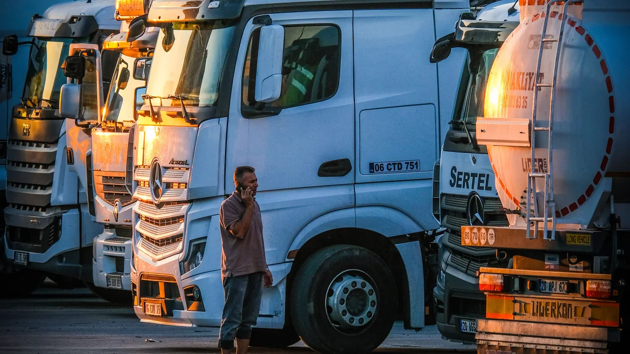 A person walking among parked trucks at sunset
